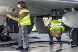 Technicians inspecting the underneath of a plane