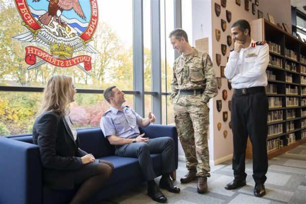 Service personnel in uniform and a civilian talking in a library