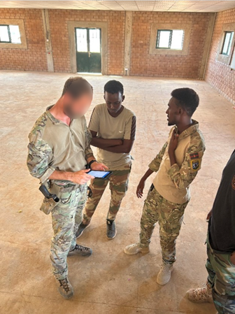 3 men in military uniform looking at a tablet computer