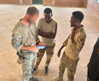 Soldiers from various countries looking at a tablet